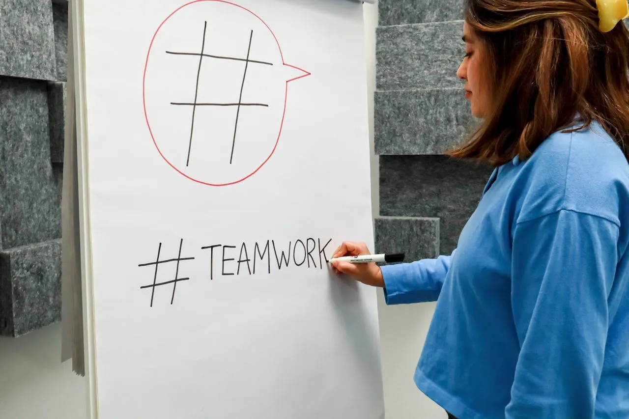 Person notiert das Wort Teamwork auf einem Flipchart